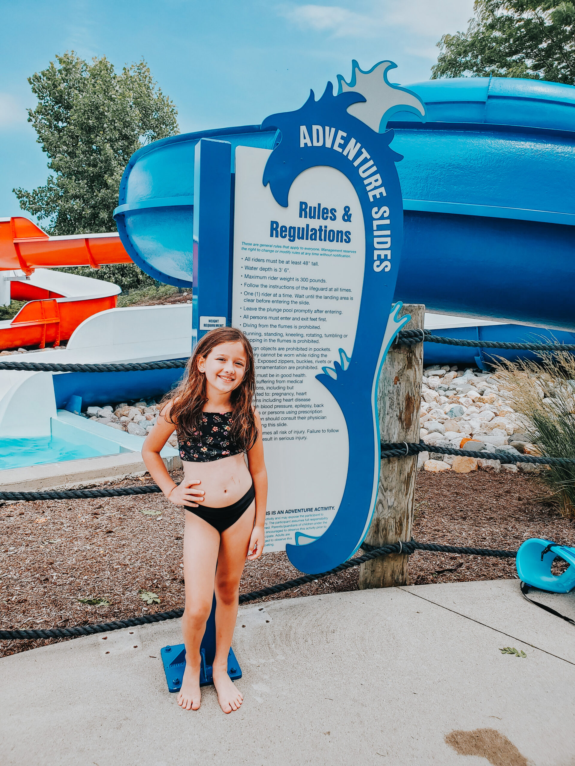 girl standing in front of the adventure slides signs