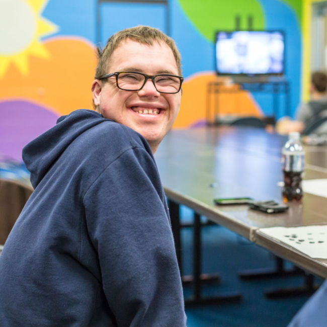 Adaptive client smiles amidst the fun at Teen Fun Night at the MCC.