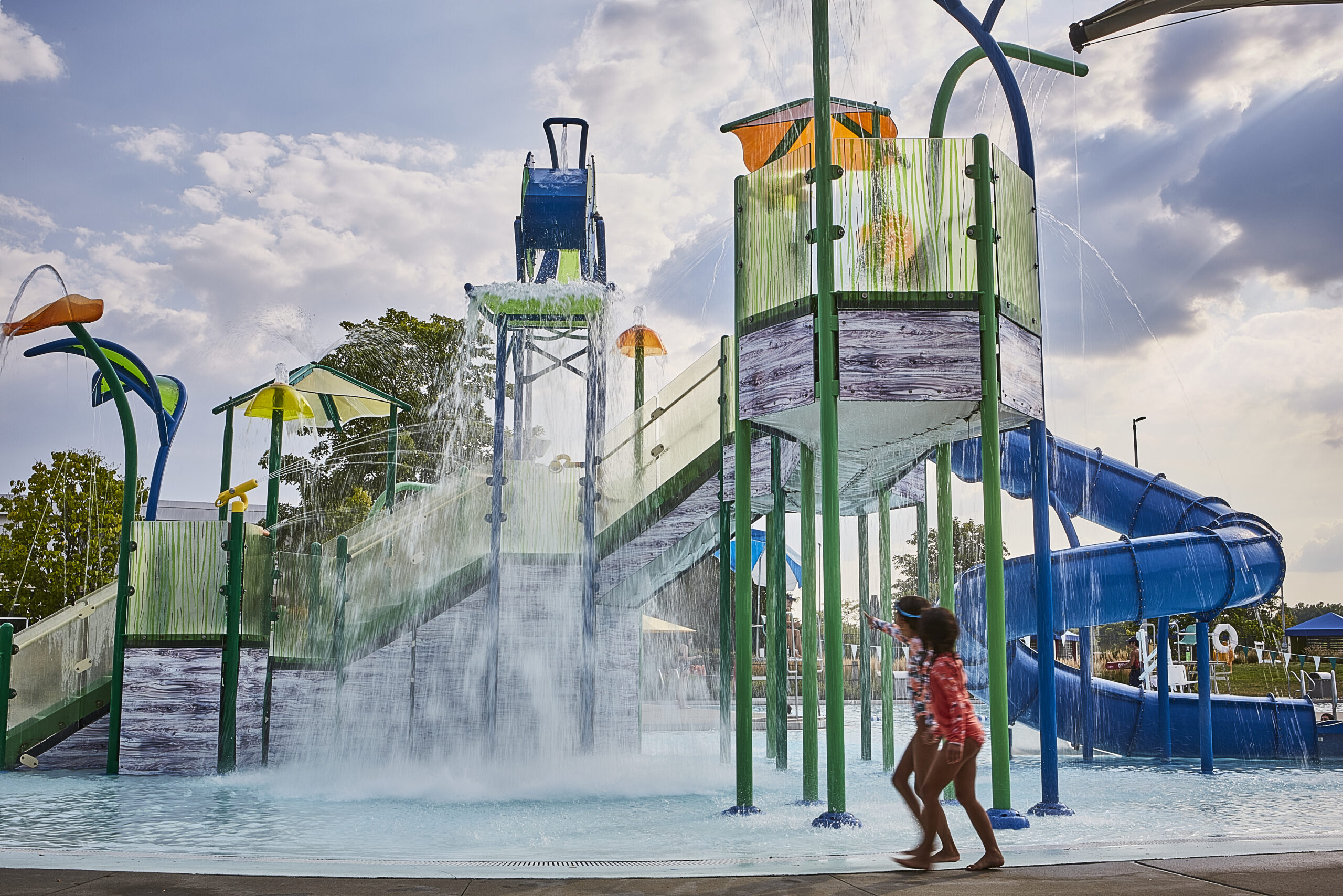 Children walk by the activity pool at The Waterpark at dusk.