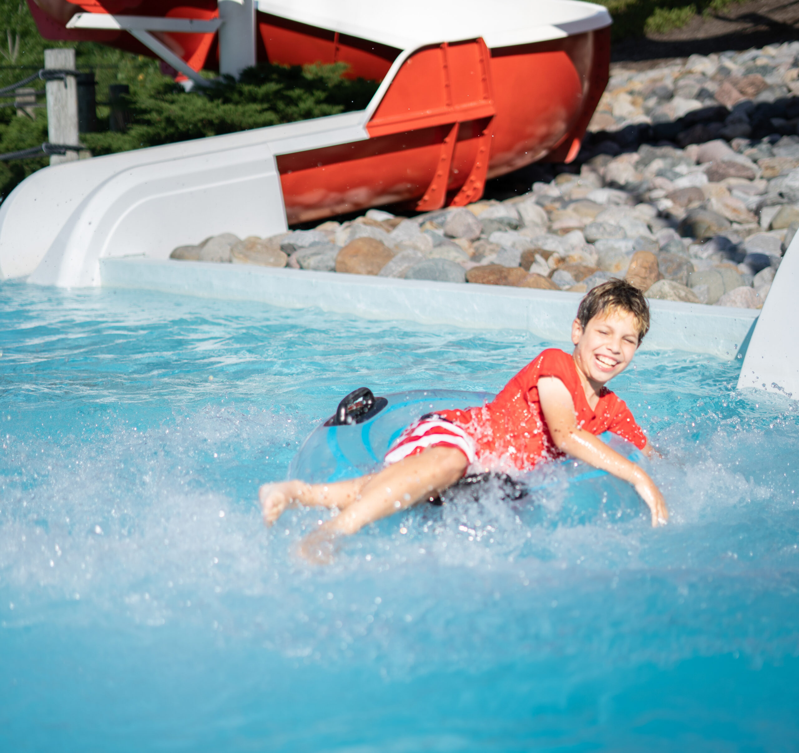boy splashes into the water below the blue adventure slide