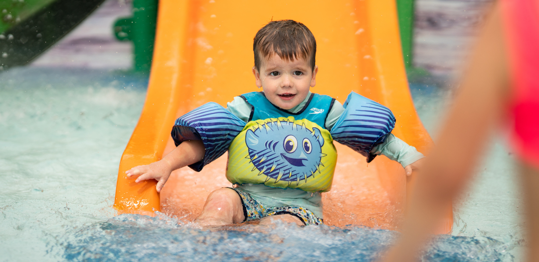 Child splashes down the orange slide at the Kiddie Pool at The Waterpark.