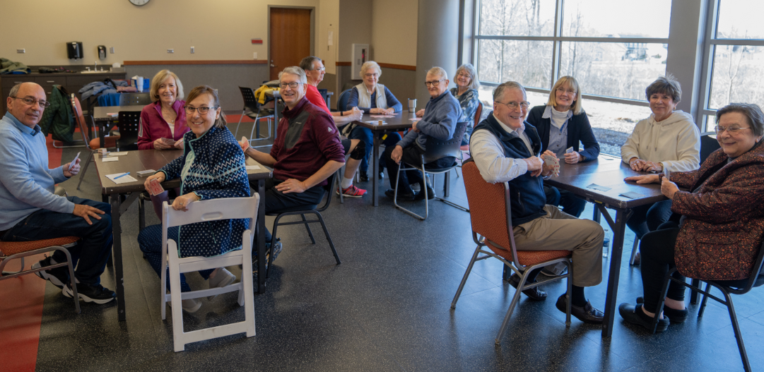 Bridge club participants smile for the camera in a classroom during club time at the MCC.