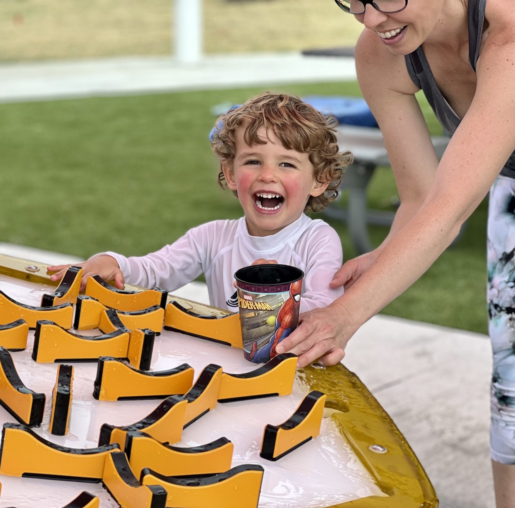 Lawrence Inlow Park child smiles and laughs as he plays with water table feature.