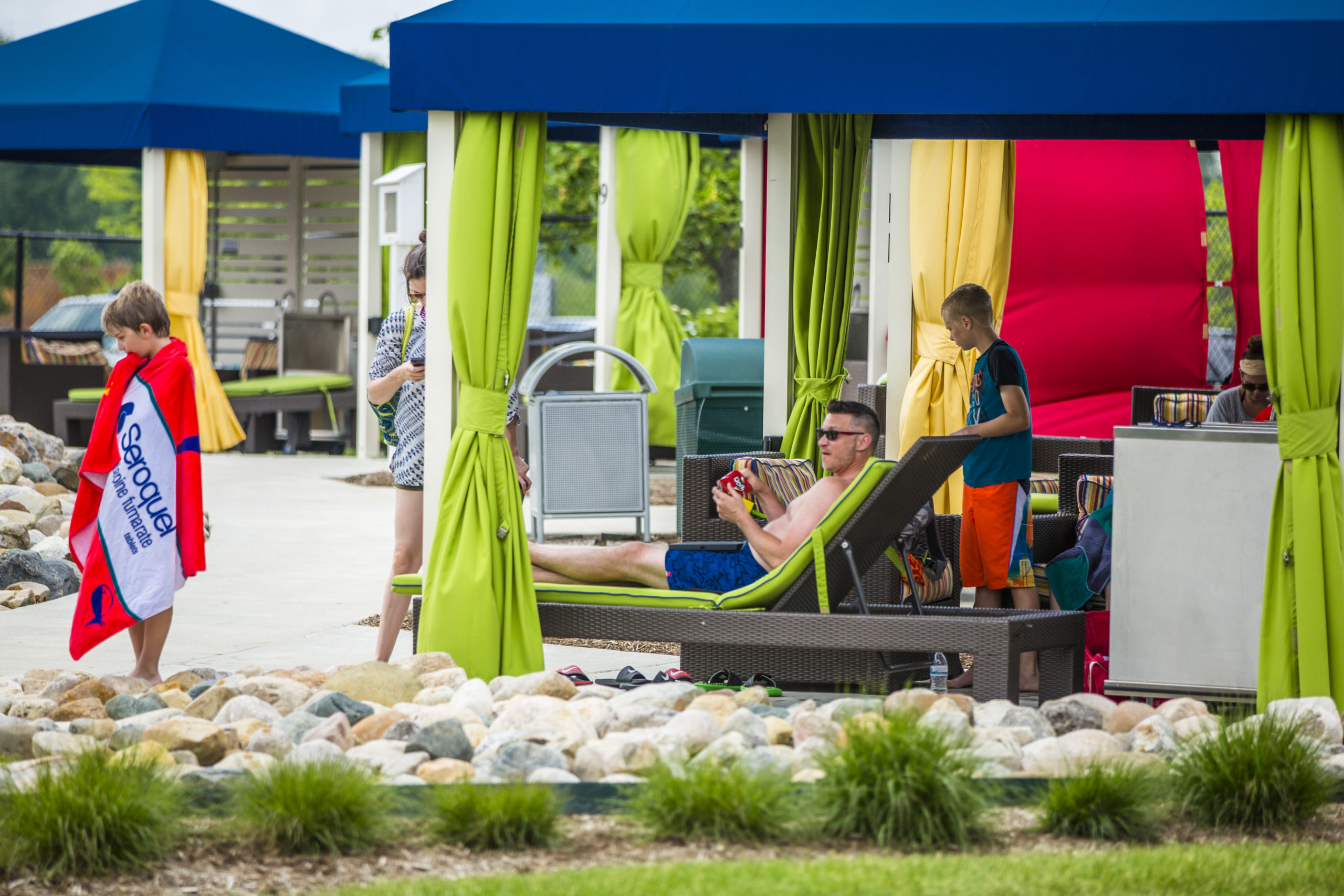 Dad and son relax and lounge in lounge chairs in one of the Waterpark cabanas.