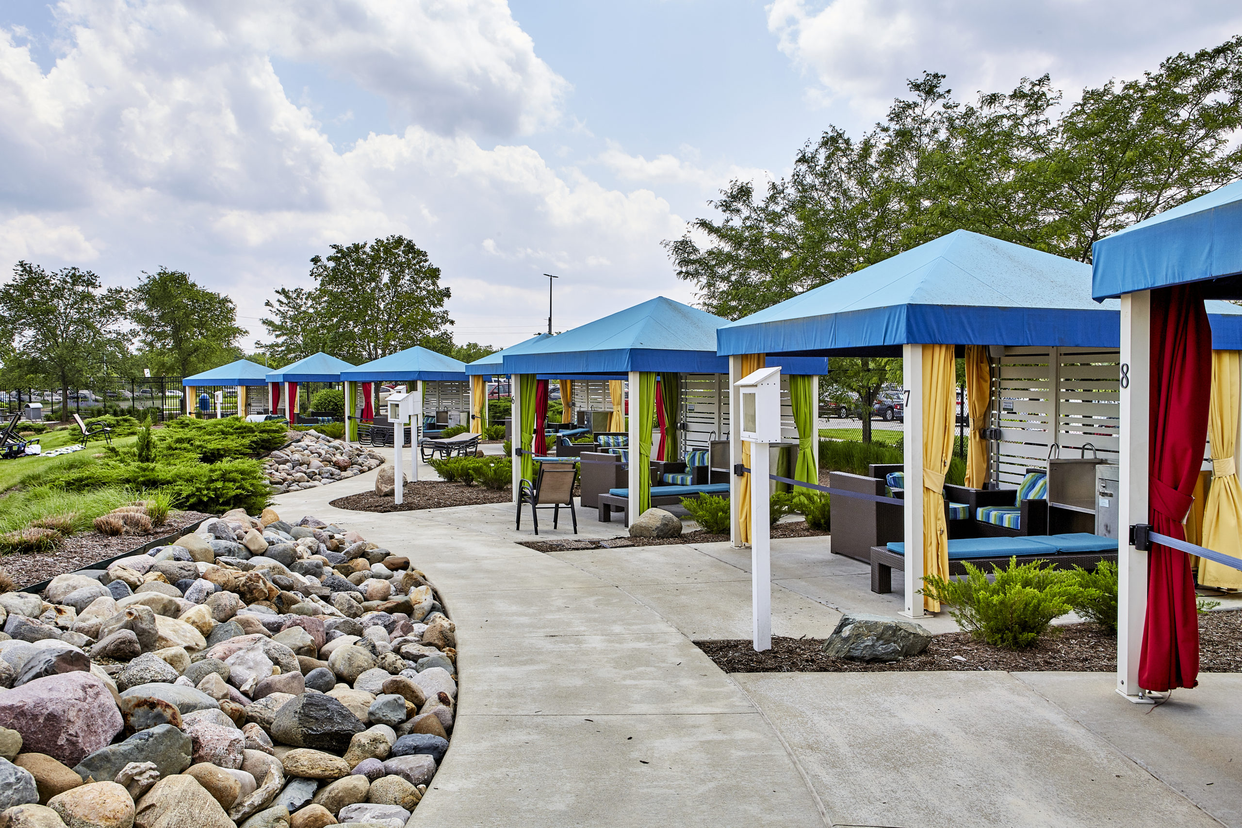 Cabanas in a row at The Waterpark, with blue tarp tops and yellow, green and red curtains.