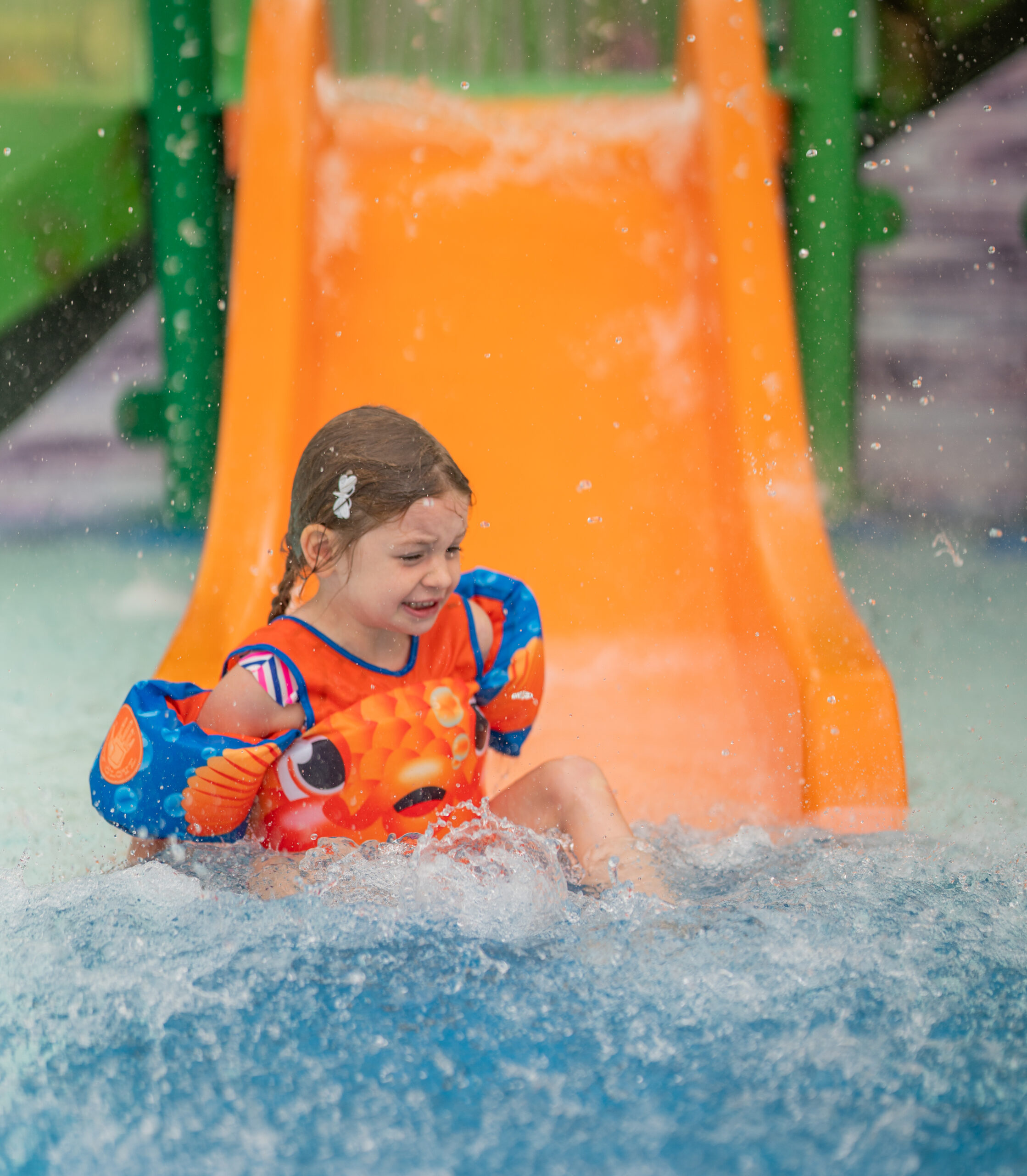 Kiddo comes down the orange slide in the Kiddie Pool at The Waterpark.