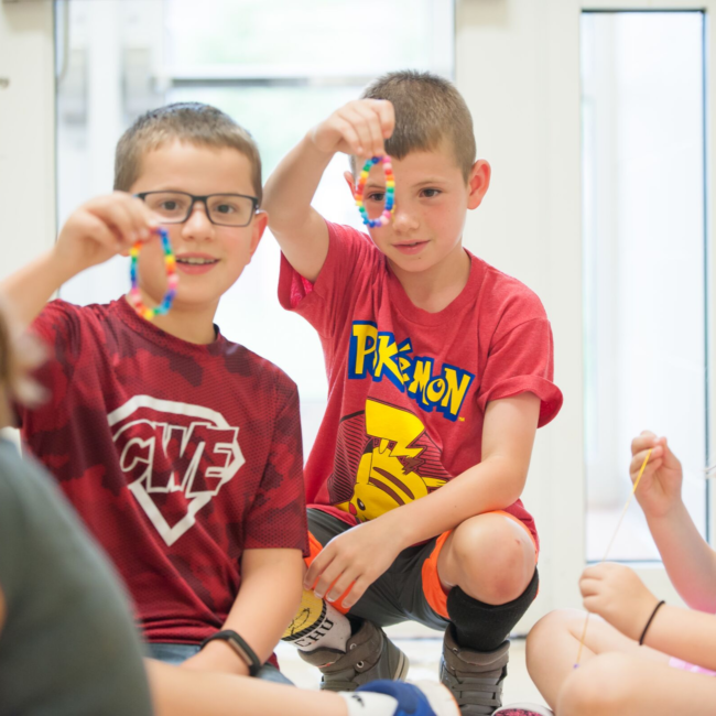 Kids building necklaces in an adventures in art summer camp