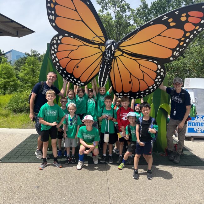 Participants pose in front of a butterfly statue.