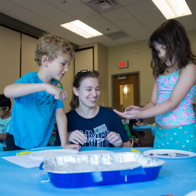 Camp counselor teaching kids science at a science of summer camp