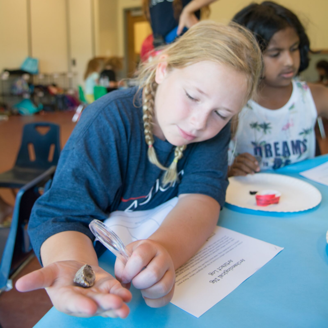 Kid studying a rock at a science of summer camp