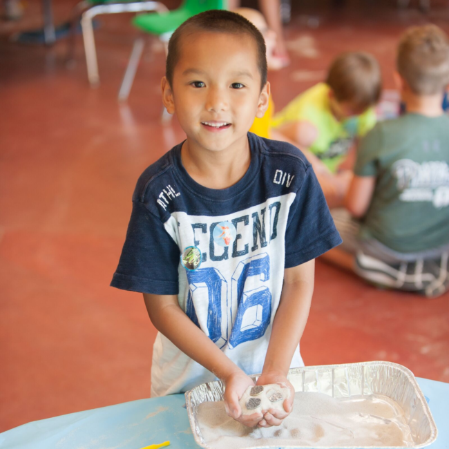 Kid smiling at a science of summer camp