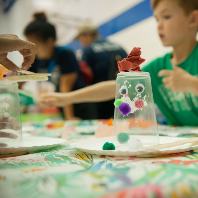 Boy smiling with his art project at the summer experience summer camp