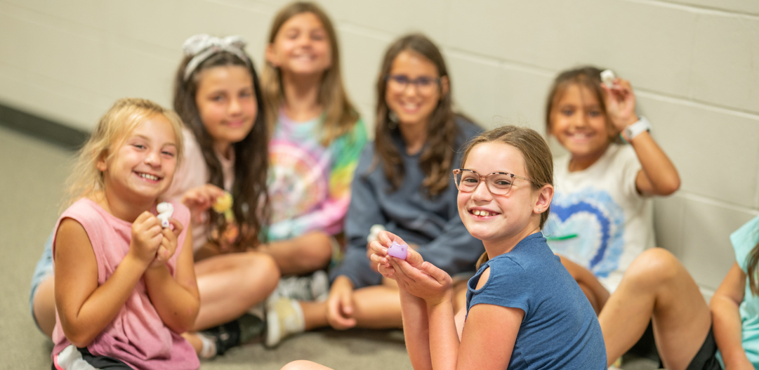 A group of campers smile while creating crafts.