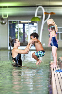 Kid jumping in the water at the pool for swim lessons