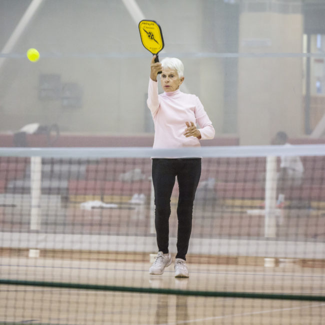 Pickleball players hits the ball across the net in the MCC gymnasium.