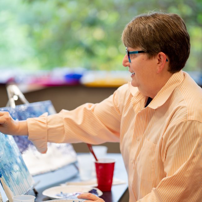 Woman paints with acrylics during an adult art series class.
