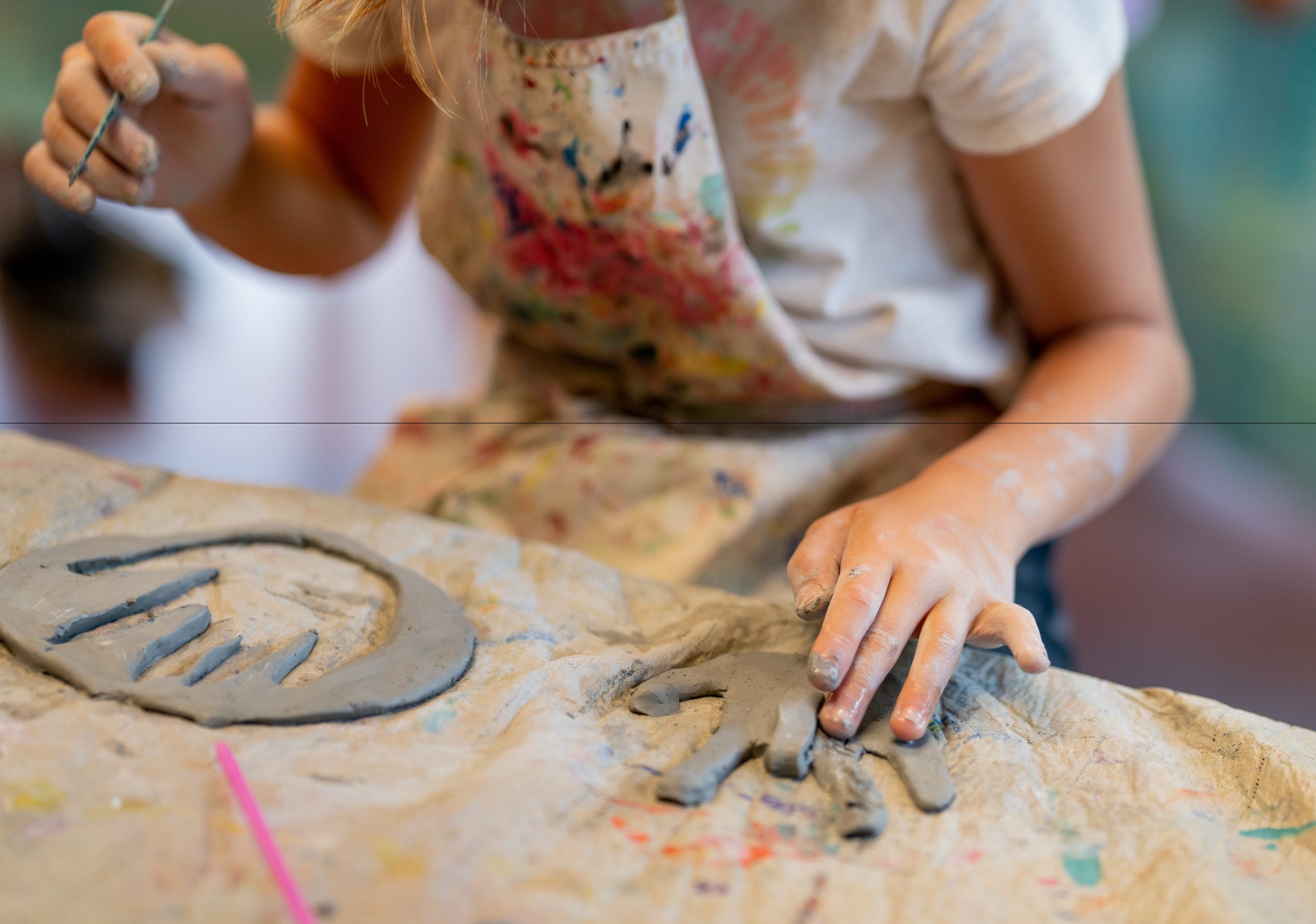 Child cuts out traced out shape of their hand in clay and forms the hand into the "I love you" sign in American Sign Language.