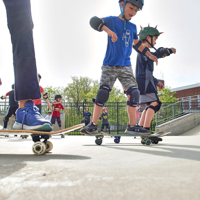 Youth skateboarders get a lesson at the skate park.
