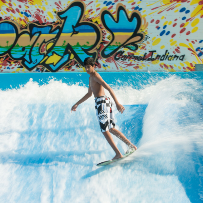 Kid surfing on the flow rider in the summer at the Waterpark