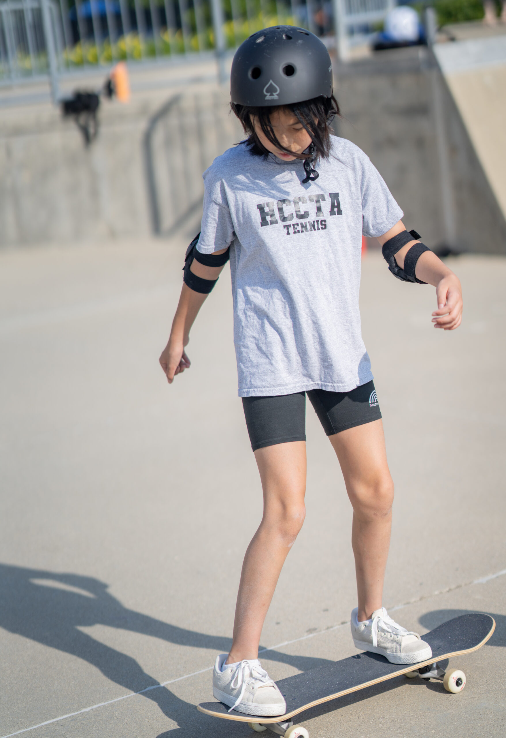 Beginner student is learning her flow on a skateboard at the skatepark during a lesson.