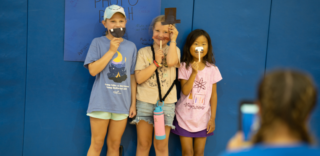 Three campers pose with photobooth props