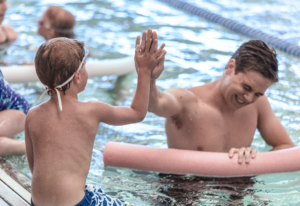 Swim instructor high fiving swim participant