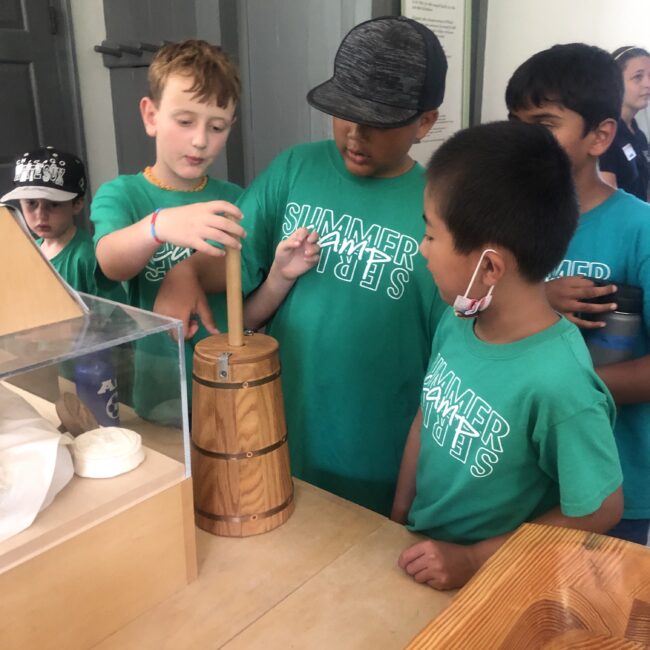 Students learn how to churn butter the old-fashioned way at Conner Prairie during Camp Wayback.