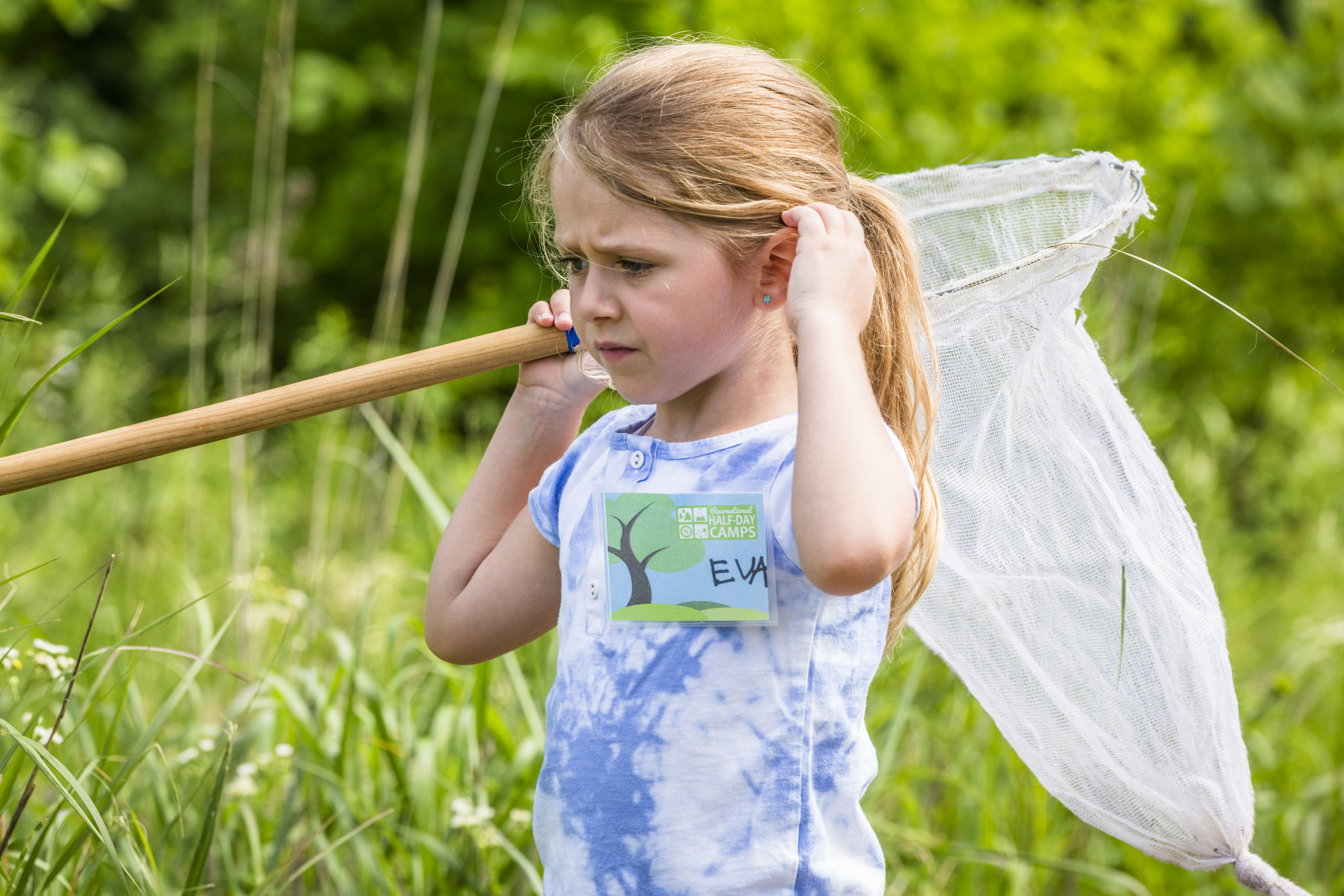 Child in a summer camp awaits with a net by the lagoon during the outdoor explorers camp.