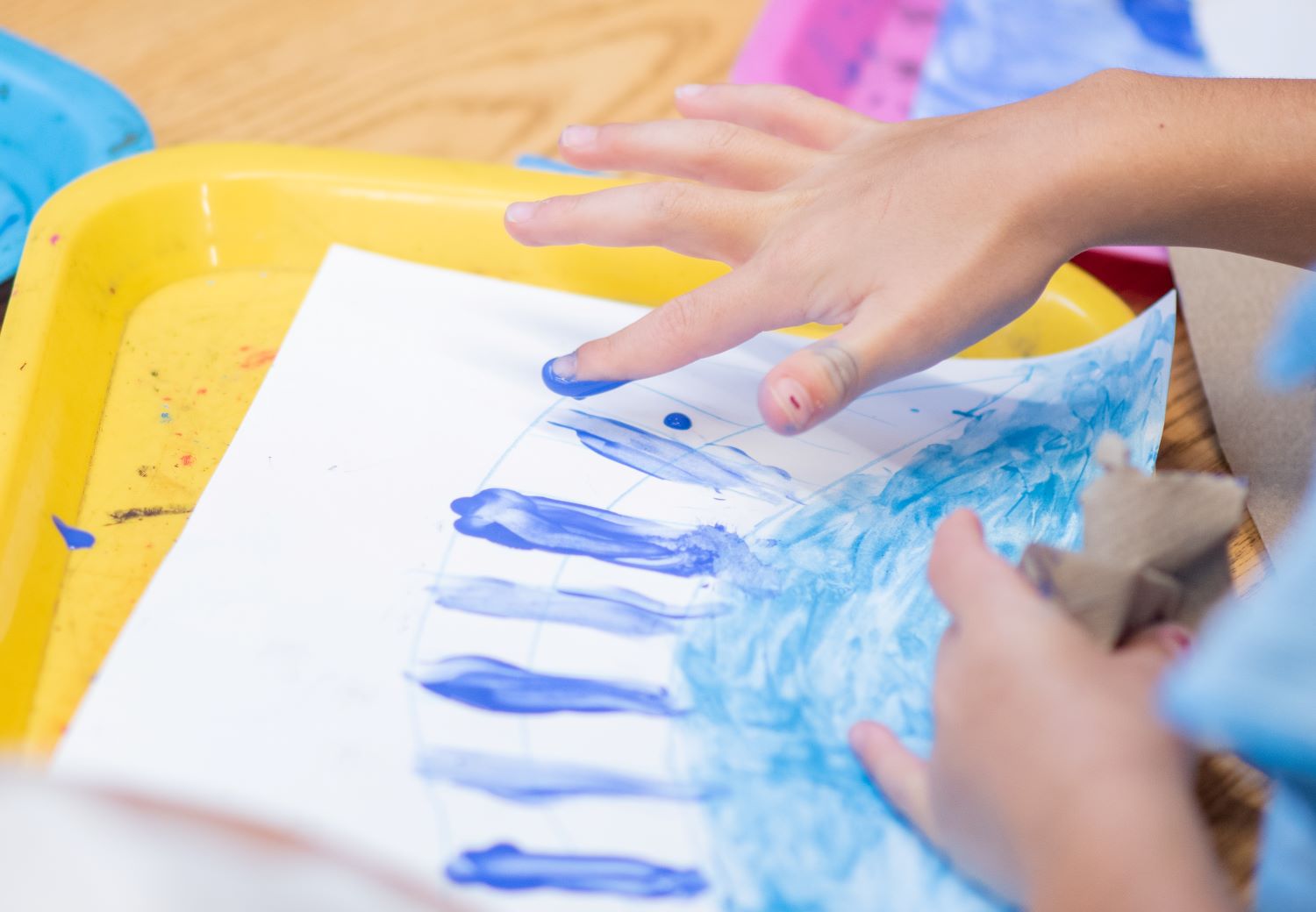 Child up close finger painting a masterpiece during steam team summer camp.