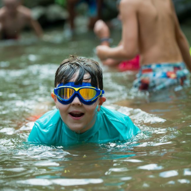 Child swimming with reflective goggles in the creek.