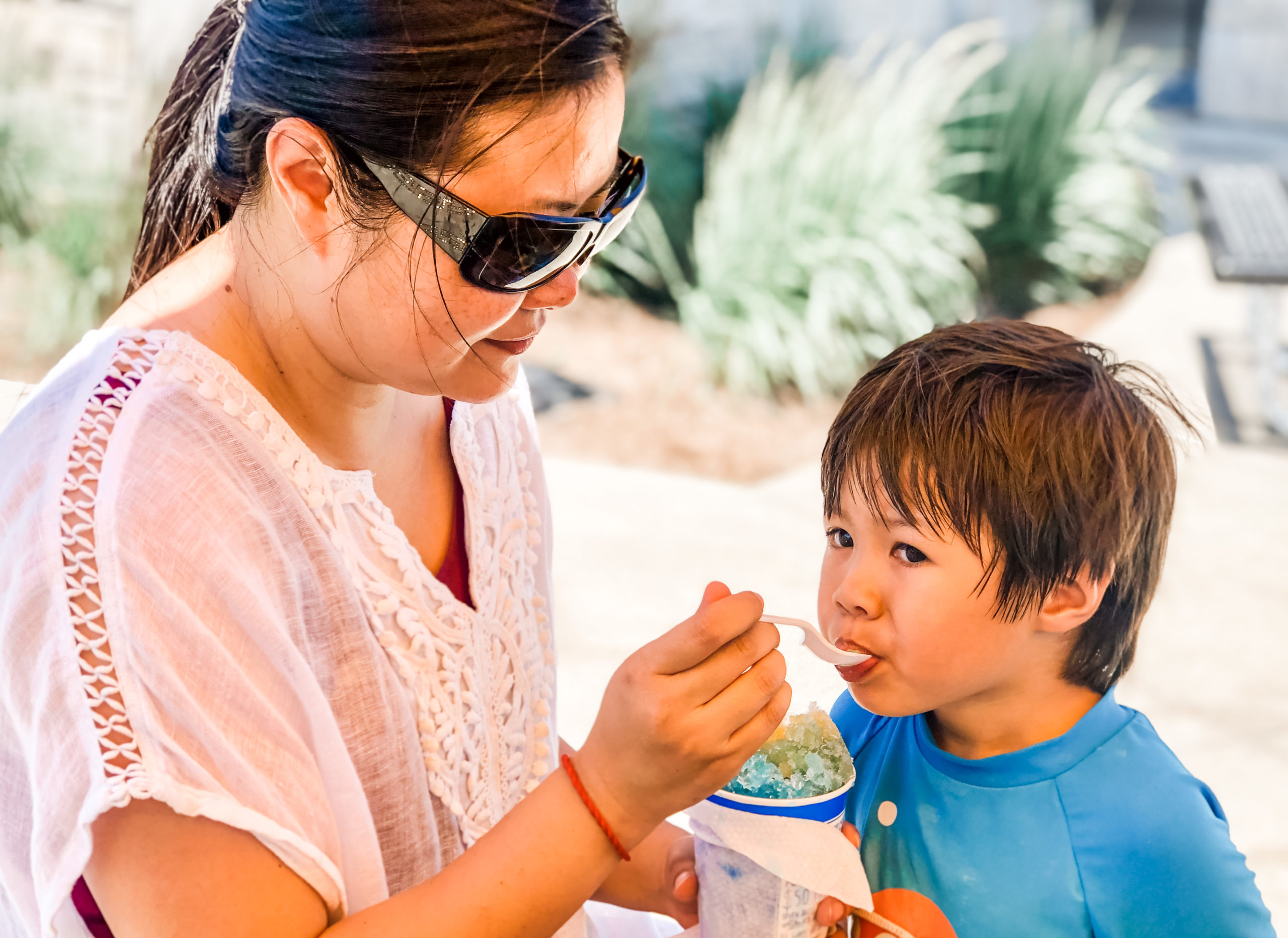 Mom feeding child kona ice snow cone