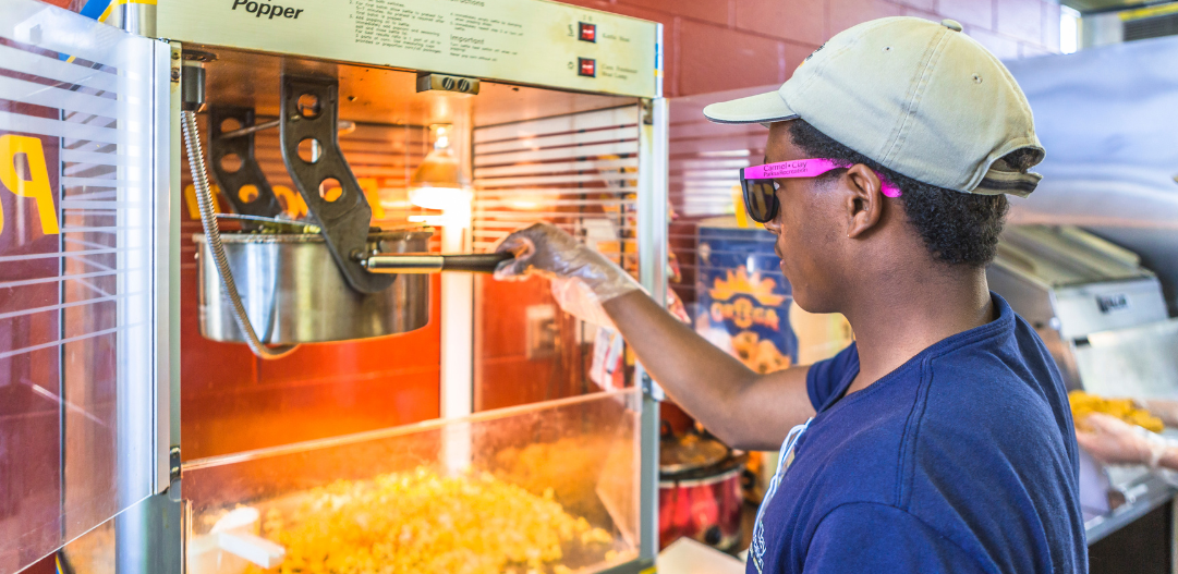 Concession stand employee pops fresh popcorn for visitors.