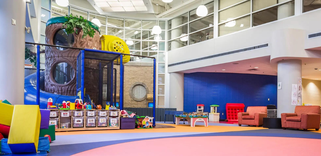 Wide view of Kid Zone at the Monon Community Center, with play structure, colorful floors, and toys.