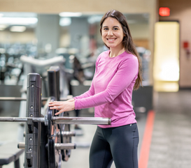 MCC member smiles at camera while changing the weights for her bench lift weightlifting routine.