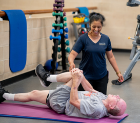 Personal trainer helps guest stretch in the fitness center.