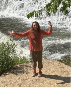 Adaptive Instructor Beth poses in front of a waterfall.
