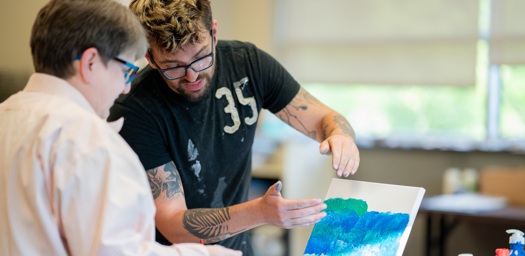 Art instructor Zachary Lowe working with an adult student on acrylic paint pouring.