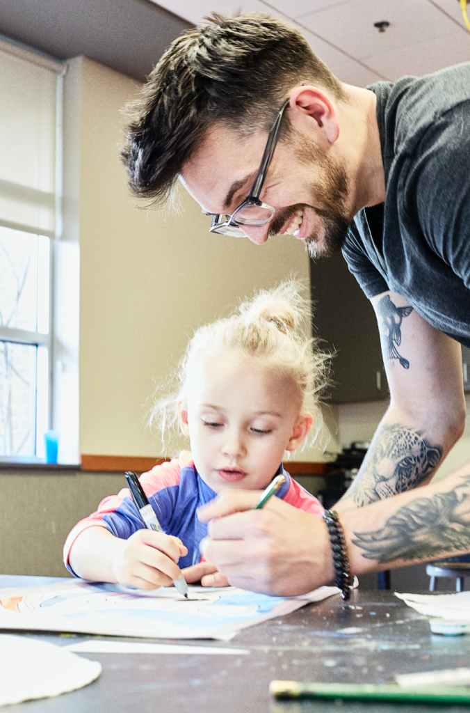 Art instructor Zachary Lowe working with youth art student on an art project..