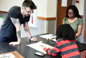 Art instructor Zachary Lowe working with youth art student on an art project..