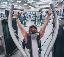 Behind point of view of woman using weight lifting machine in the fitness center at the MCC.