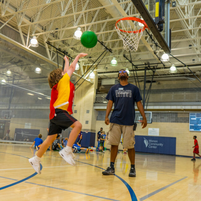 Participant goes for the big shot while playing basketball at camp Kids at Play.