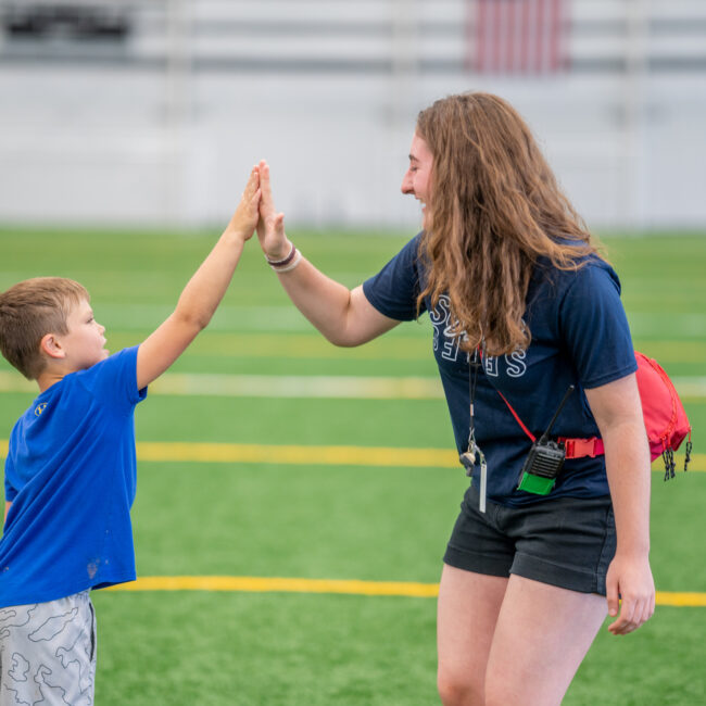 Camp instructor high fives a camper at In the Zone sports camp.