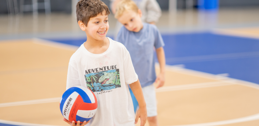 Summer camper holds a volleyball.