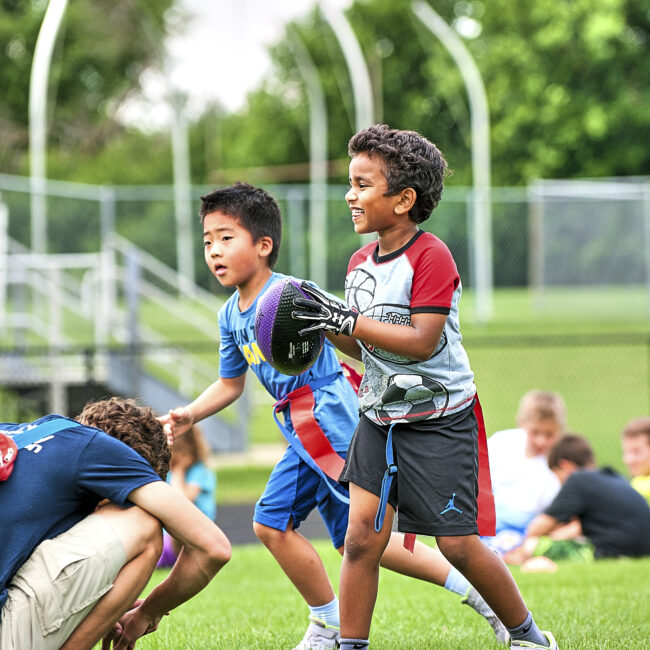 Participants run across the field during flag football during Kids at Play camp.