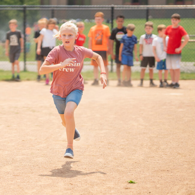 Participant running across the field during kickball at In the Zone summer camp.