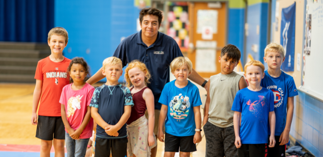 Summer Camp Counselor with several kids after a game of dodgeball in the gym.