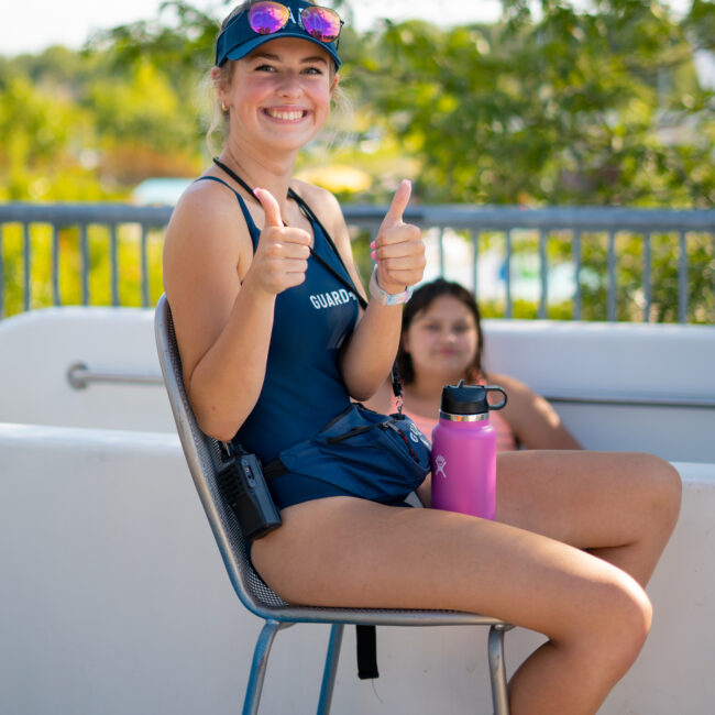 Lifeguard smiles and gives a thumbs up at the top of the water slide.