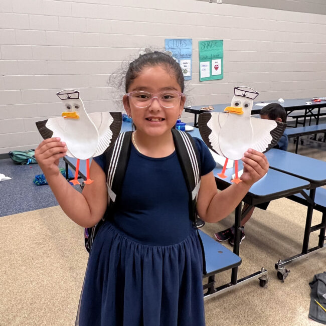 Child holds up a bird craft that they made at ESE.