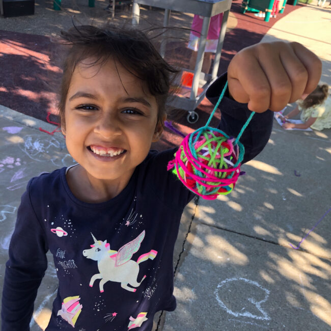 ESE child holds up a craft project to the camera.