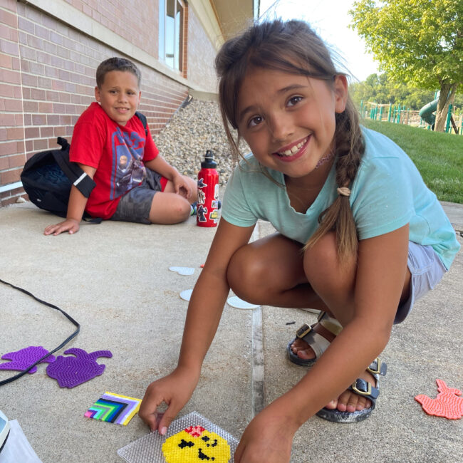 ESE after school participant works on a smiley face craft.